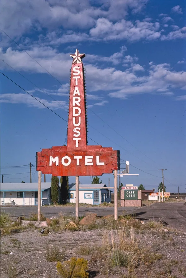 A tall red Stardust Motel sign topped with a star, against a blue sky in Marfa