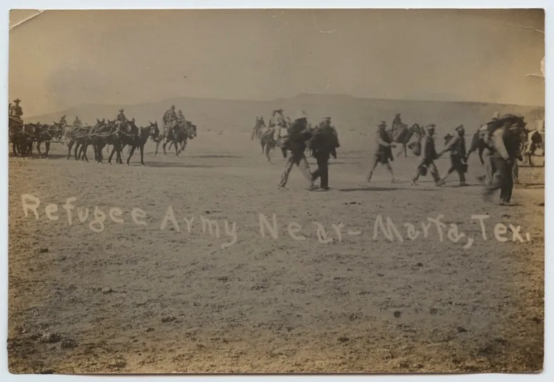 Sepia photograph of soldiers, pack mules and people on foot crossing open desert, captioned Refugee Army Near Marfa, Tex.