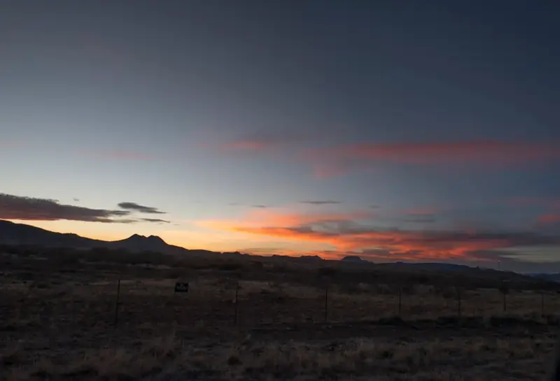 Dark mountain silhouettes under an orange and blue sunset sky in Brewster County