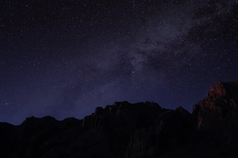 The Milky Way rising over a jagged dark ridge under a sky full of stars